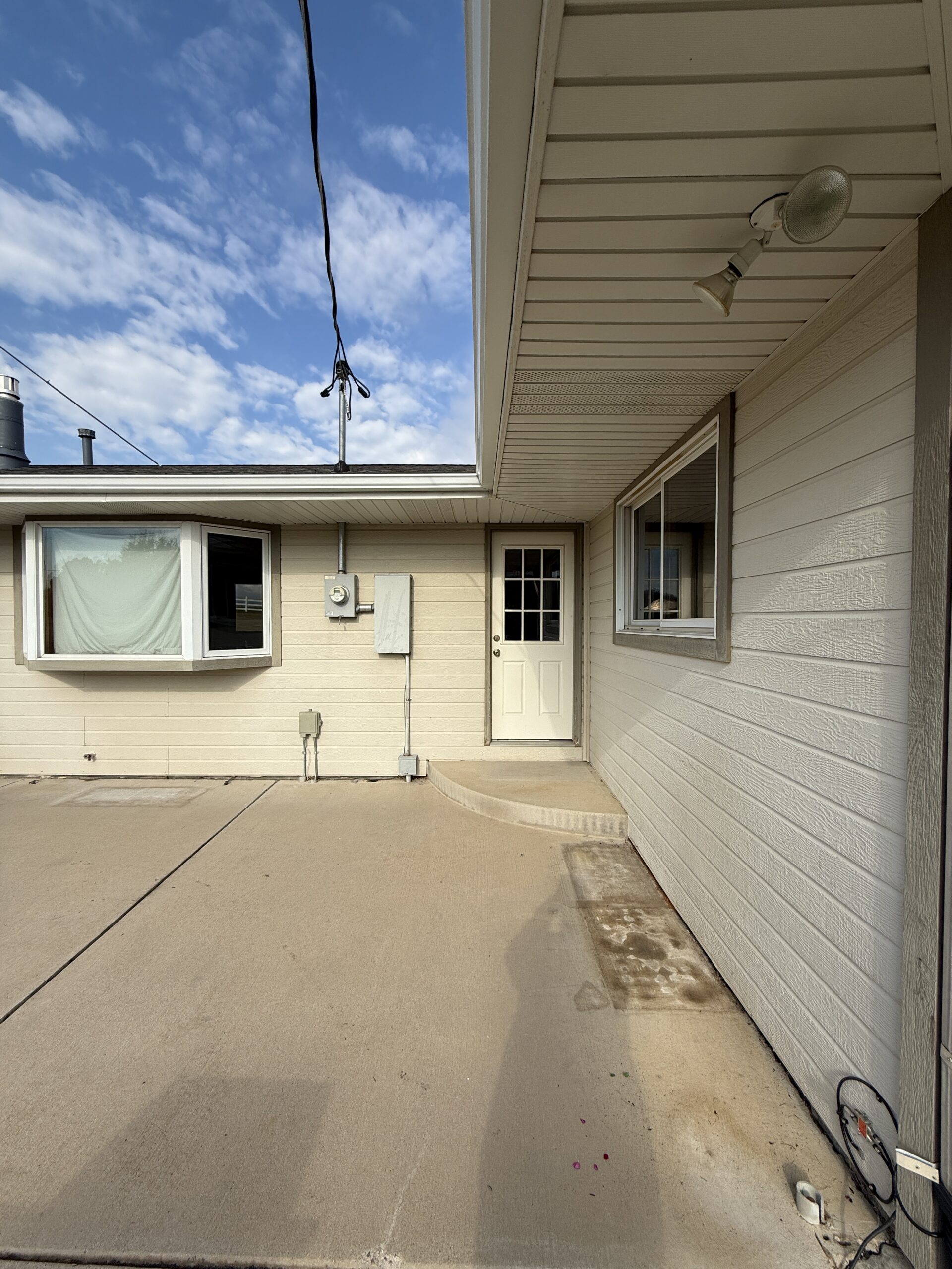 Professional Exterior House Painting Services for Homes Project Exterior view of a residential house with light beige siding and a white door, ready for painting.
