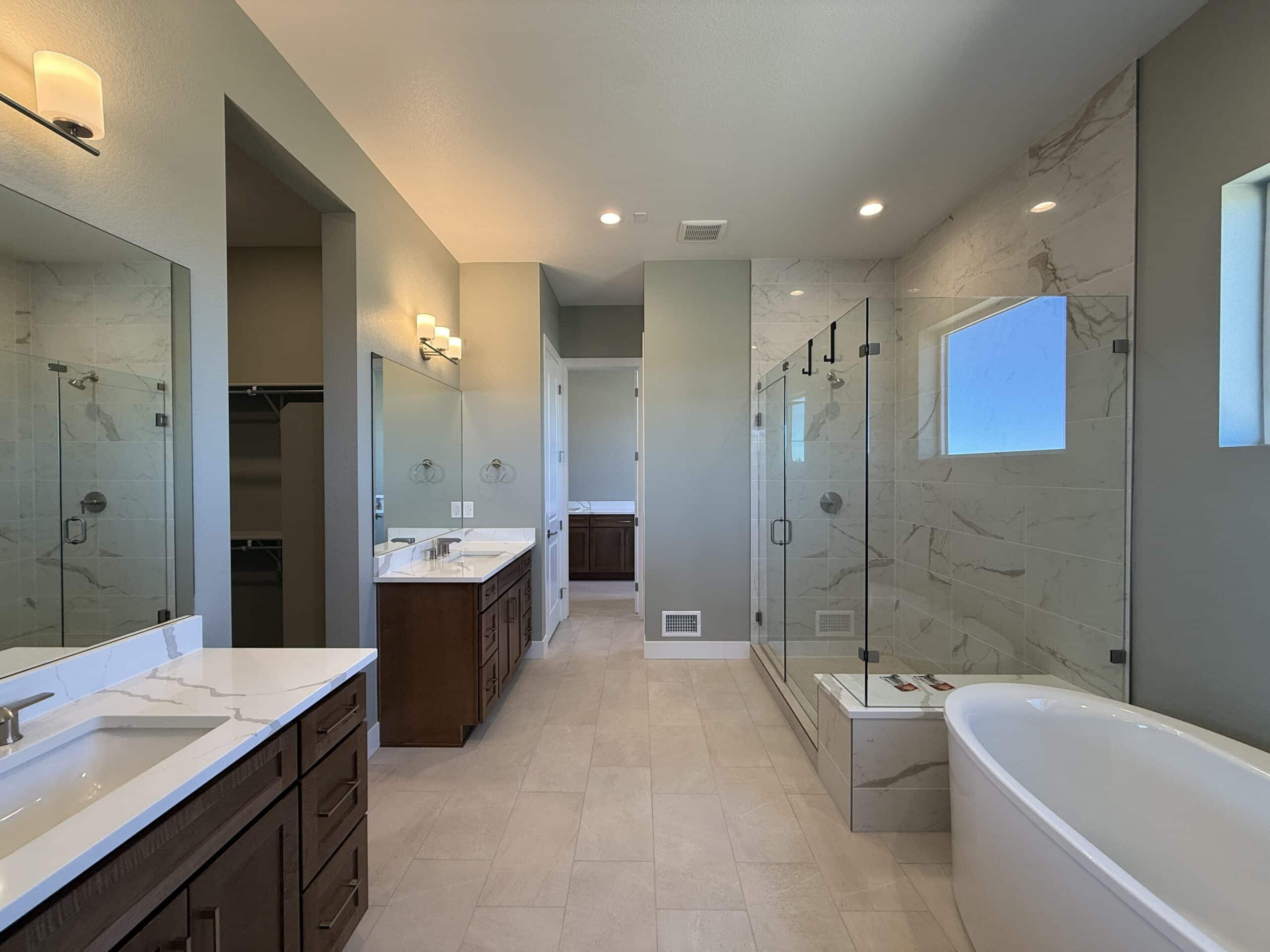 Elegant master bathroom with freshly painted light green walls, dual vanities, and a luxurious walk-in shower.
