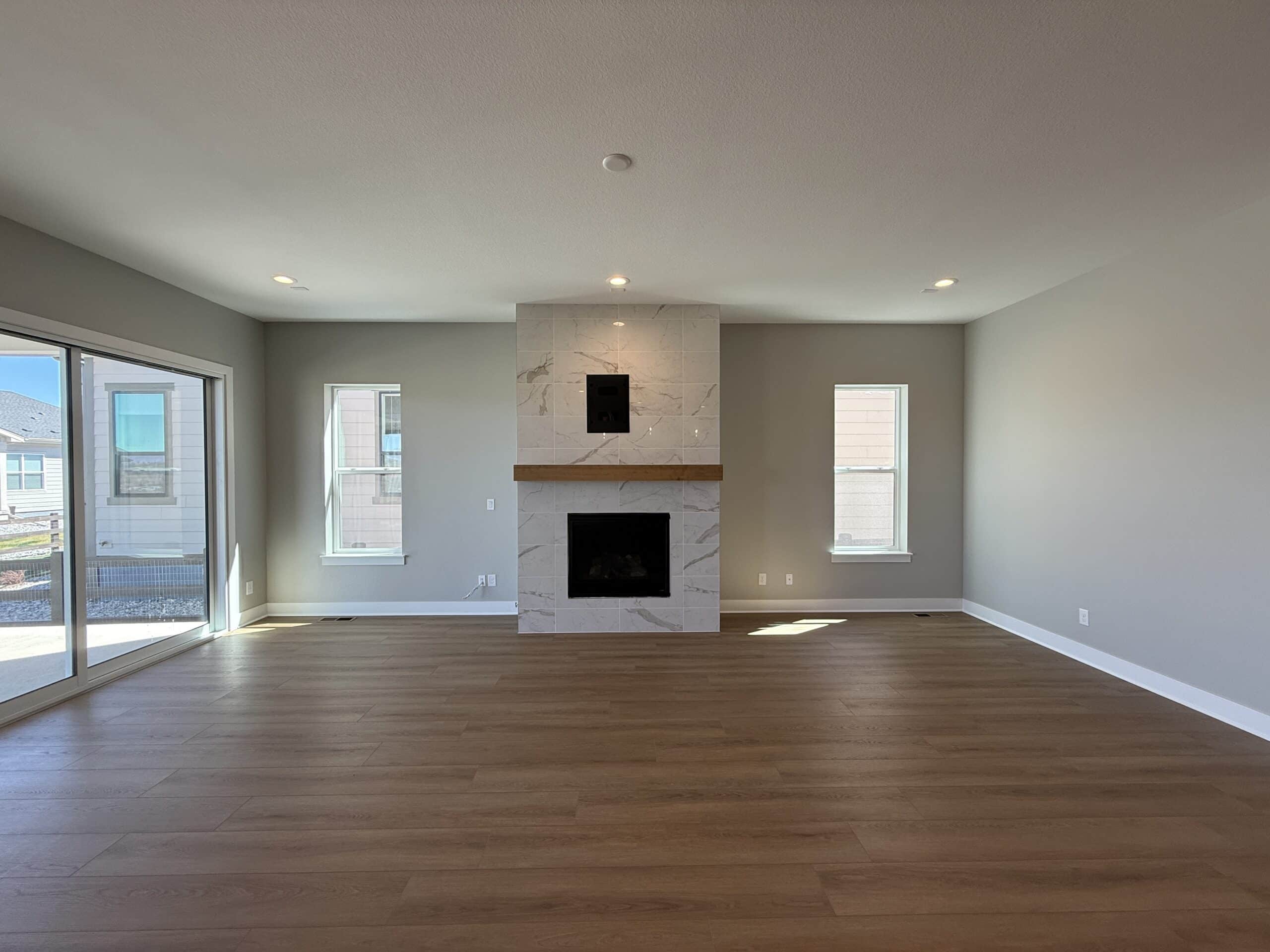 A freshly painted modern living room with light gray walls, a tiled fireplace, and hardwood floors.
